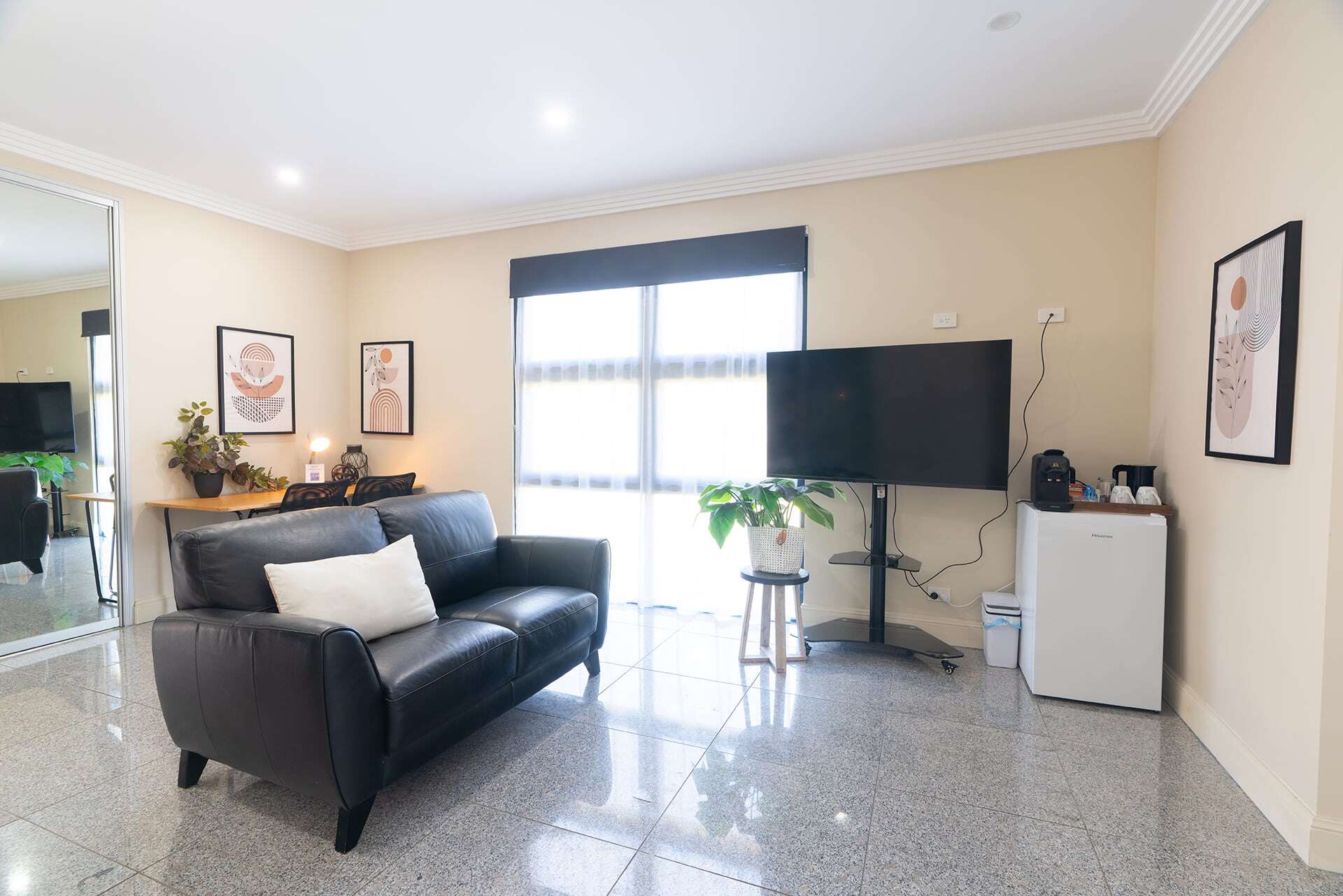 Home 5 Bright living room with large window, TV, potted plant, and stylish decor.