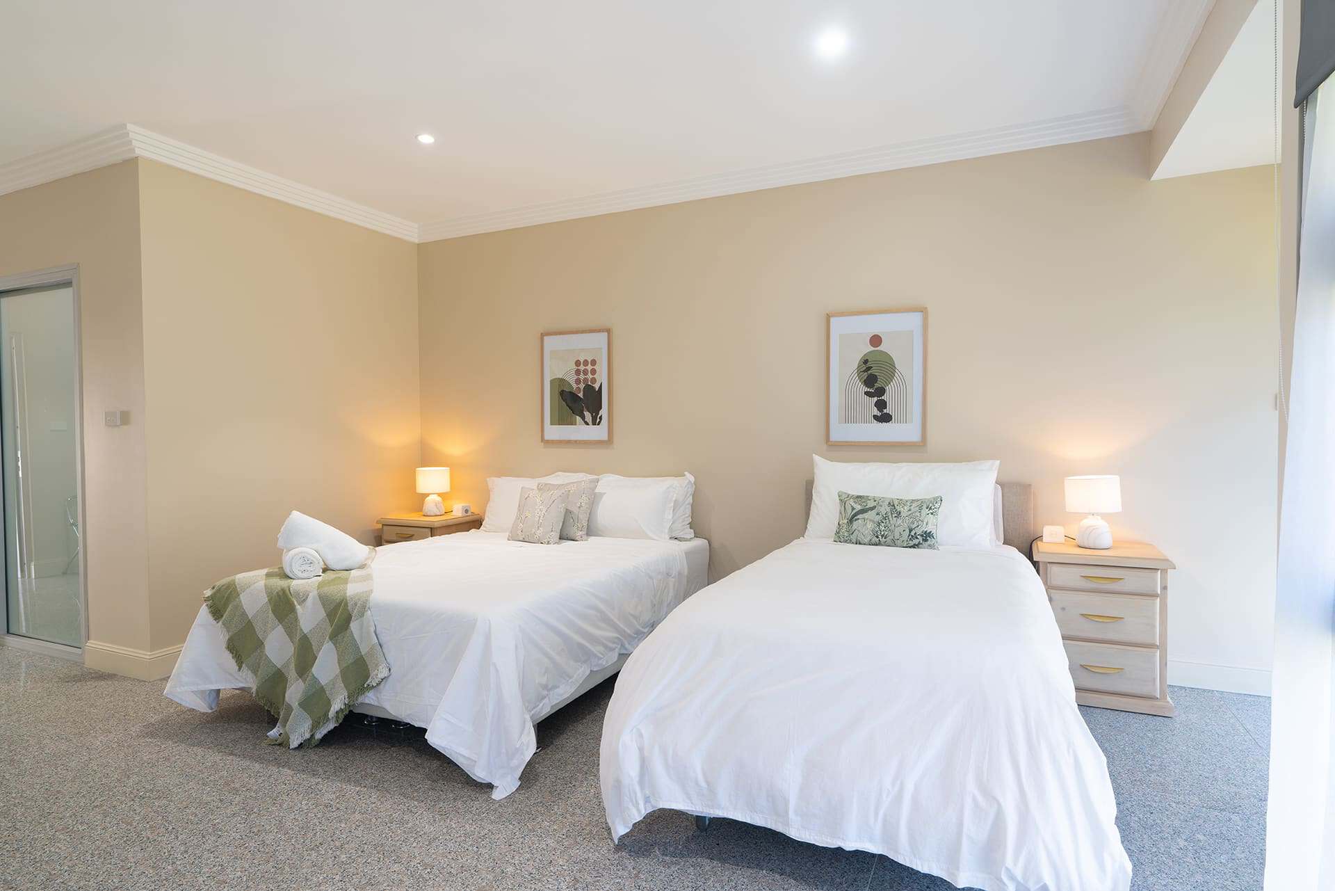 Home 8 Bright, inviting hotel room featuring two queen beds with beige decor. Perfect for relaxing stays at UnleashedX.