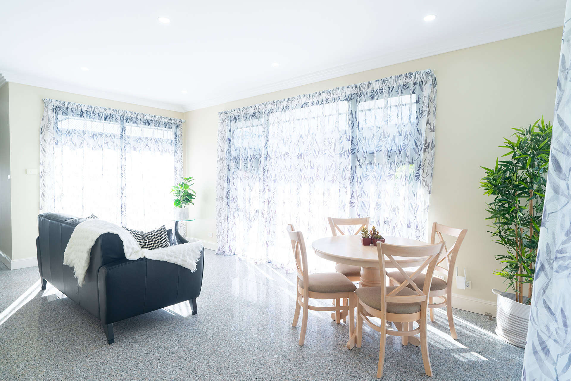 Home 11 Bright living room with large windows, sheer curtains, and cozy furniture setup.